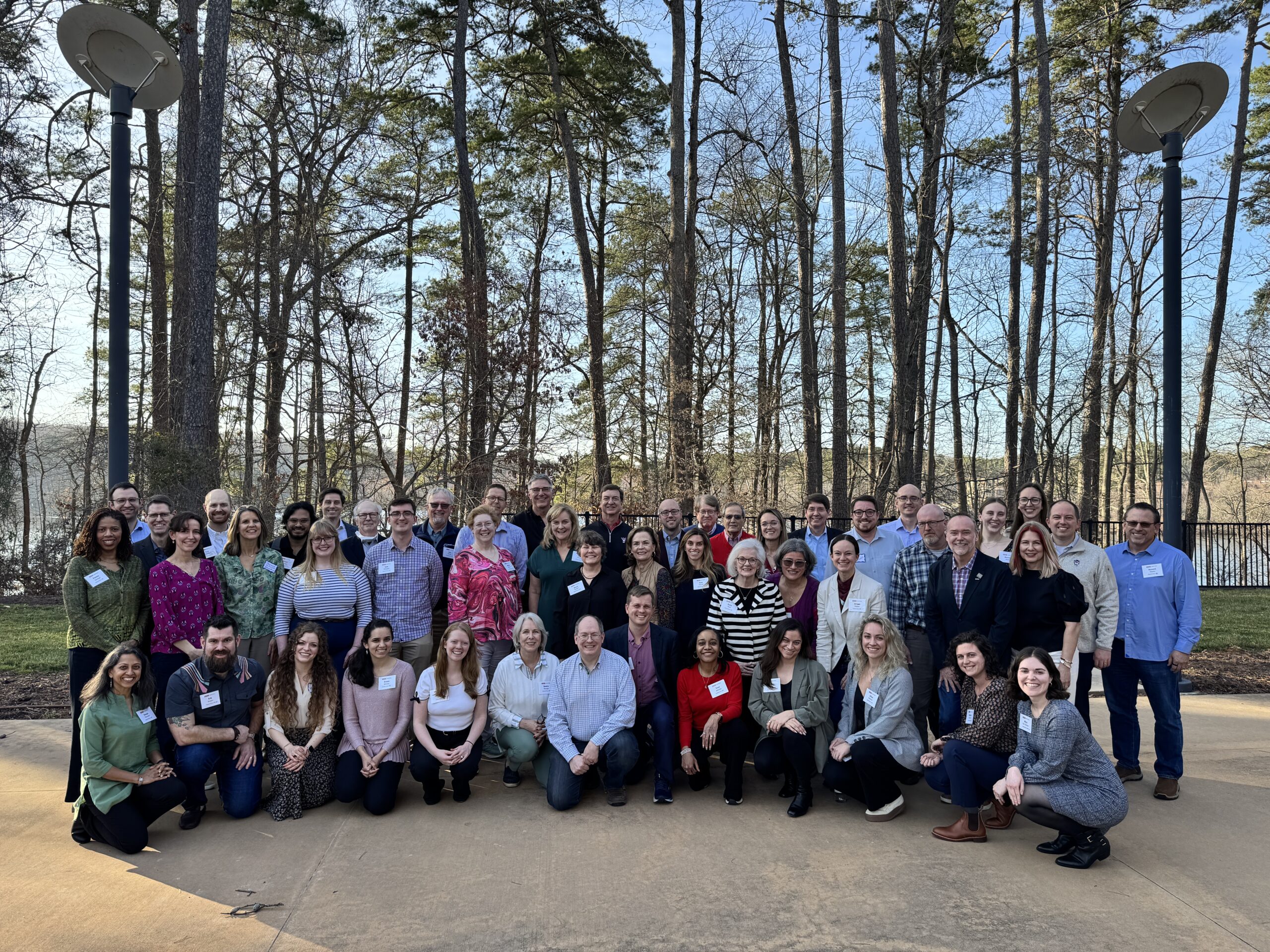 A group of Caldwell alumni gathered outside in front of trees.